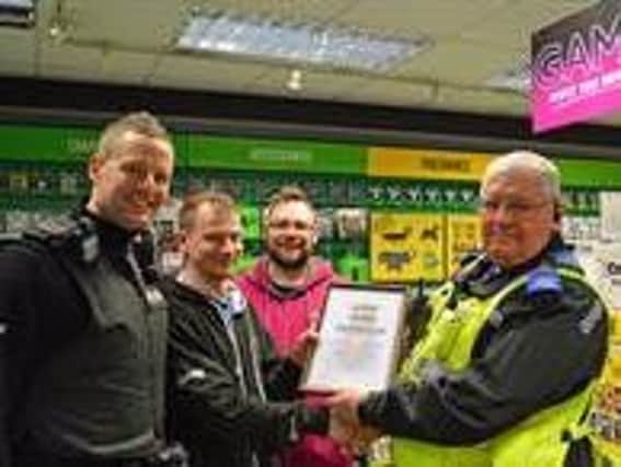 Derbyshire police present the staff at Game in Chesterfield with a certificate of thanks for helping them to catch a man wanted for fraud and theft.