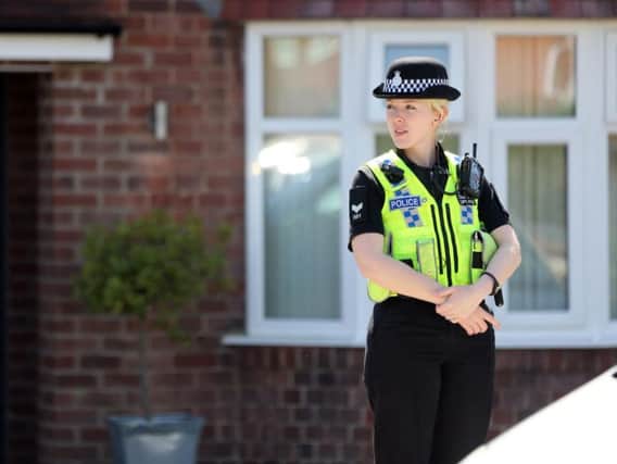 A female police officer stands guard outside a house being searched as part of a missing person inquiry