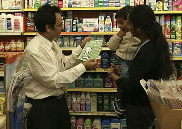 Pharmacist giving health information leaflet to woman holding child.