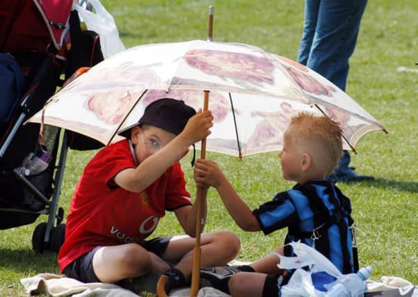 Two young lads at the Ashfield Festival Of Sports Day hide from the sun under an umbella. June, 2006.