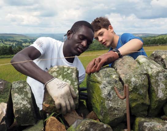 Refugees from British Red Cross helping repair a wall near Froggatt: Yaqoob Adam (left) and National Trust volunteer Tim Hartog working on the final coping stones