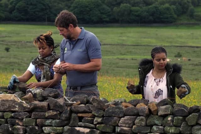 Refugees from British Red Cross helping repair a wall near Froggatt: National Trust ranger Mark Bull helping Saba Zaray (left) while Aziebe Yemane gets on with the work