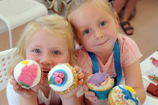 Evie Hill, left, and Lily Kendall, both five, show off their decorated cupcakes which they created with the help of Phyllis.