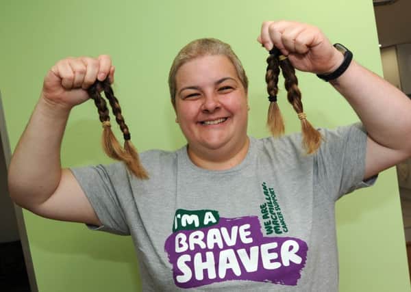 Sarah Robinson holds aloft her hair, cut in aid of Macmillan Cancer Support and to be donated to the Little Princess Trust.