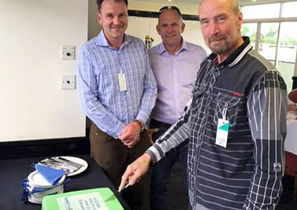 HAPPY HALF-CENTURY -- longest-serving employee John Wilde cuts the 50th birthday cake, watched by directors Tim and James Pugh-Lewis.