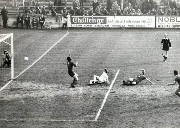 Malcolm Darling, in white, is pictured sliding in to steer the ball past Peterboroughs Eric Steele
