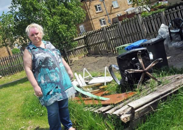 Julie Hall with the broken fence from her Paddlington Court home in Barrow Hill, which has not been removed by the council dispite requests and is attracting other dumped rubbish.
