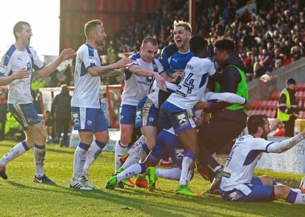 Chesterfield players mob Reece Mitchell after his injury time winner at Swindon in March.