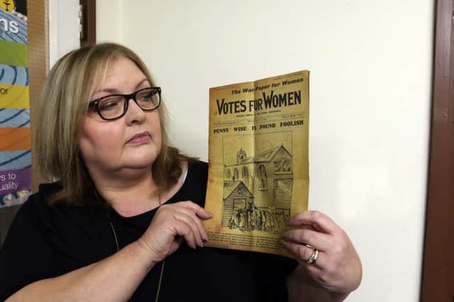 Sarah Hartley holding a votes for women paper.