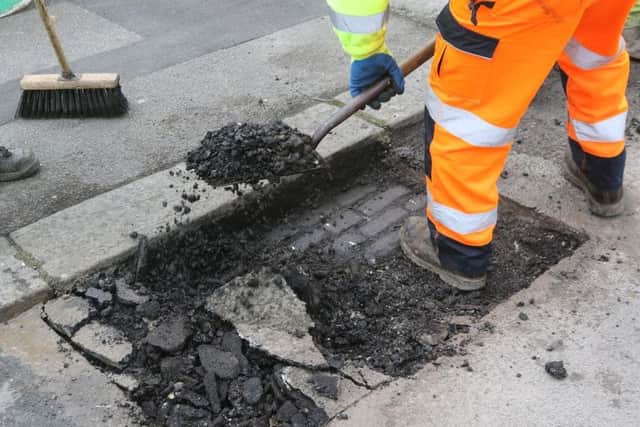 Workmen clear out a pothole before refilling it.