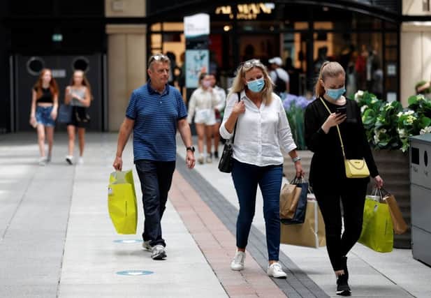 Shoppers, some wearing face masks, walk past recently reopened shops (Photo: Getty)